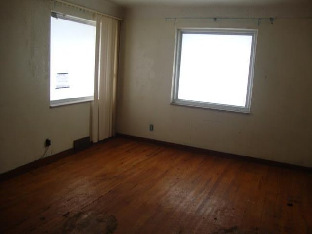 empty room featuring a healthy amount of sunlight and dark hardwood / wood-style flooring