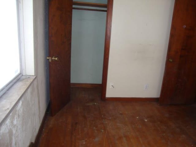 unfurnished bedroom featuring dark wood-type flooring and a closet