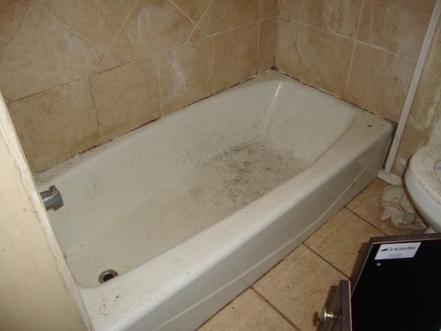 bathroom featuring a bathing tub, tile patterned floors, and toilet