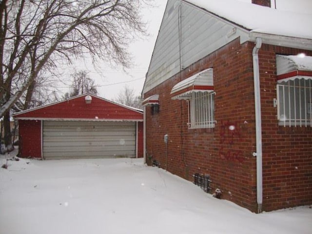 view of snow covered exterior with an outbuilding and a garage