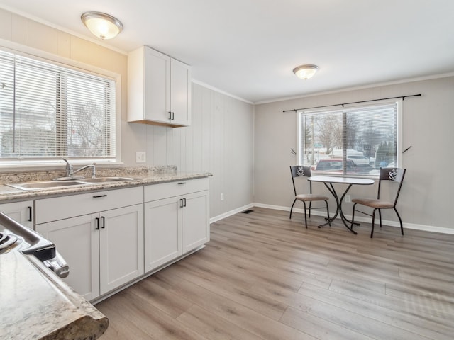 kitchen with white cabinetry, sink, crown molding, and light hardwood / wood-style floors