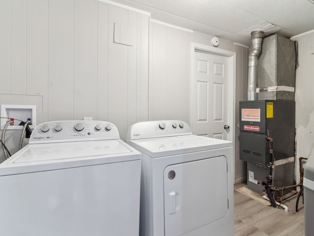 clothes washing area with separate washer and dryer, light hardwood / wood-style flooring, and heating unit