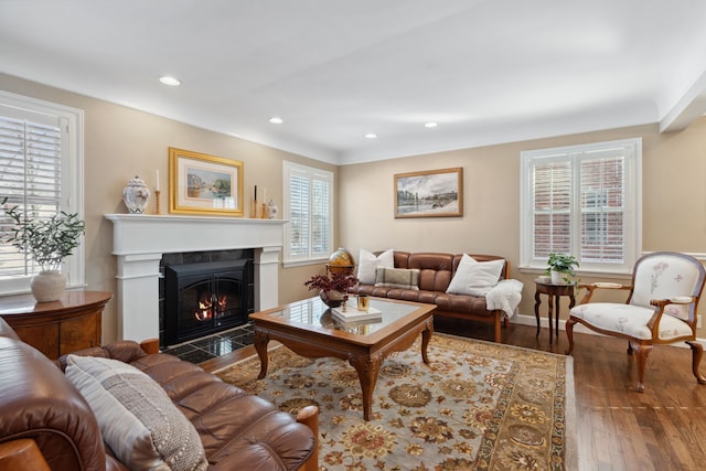 living area with baseboards, wood finished floors, recessed lighting, and a fireplace with flush hearth