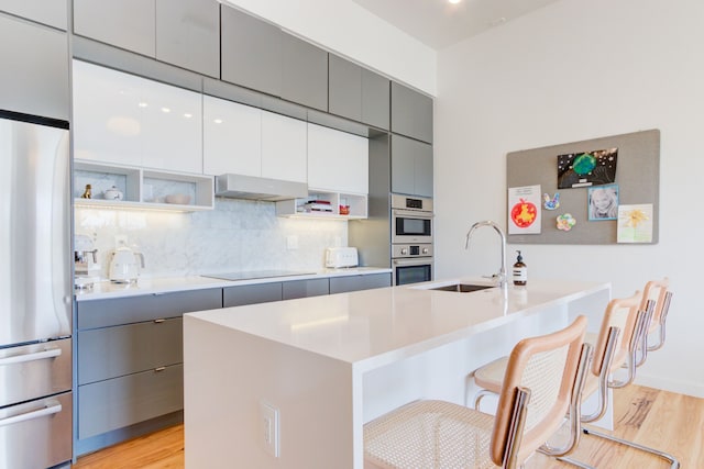 kitchen featuring extractor fan, sink, a kitchen breakfast bar, stainless steel appliances, and a center island with sink