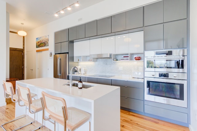 kitchen featuring a kitchen island with sink, sink, a kitchen breakfast bar, and appliances with stainless steel finishes