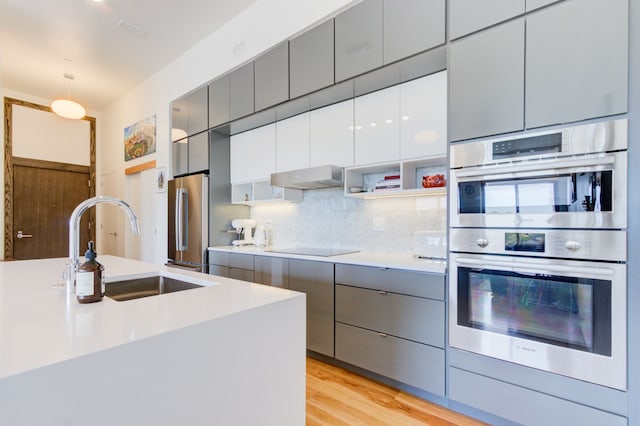 kitchen with sink, gray cabinets, appliances with stainless steel finishes, tasteful backsplash, and decorative light fixtures