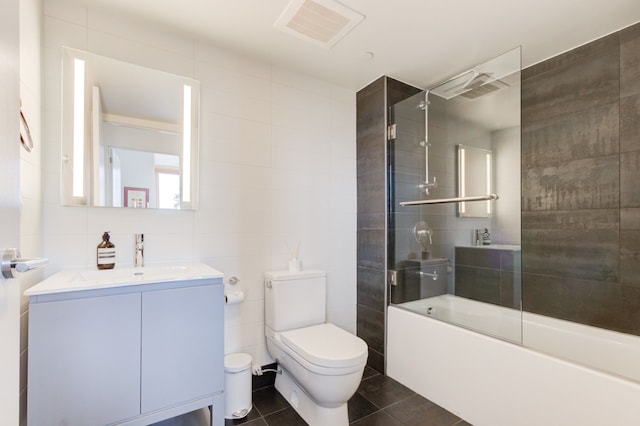 full bathroom featuring shower / bath combination with glass door, tile walls, vanity, tile patterned floors, and toilet