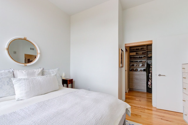 bedroom with vaulted ceiling, wood-type flooring, a walk in closet, and a closet