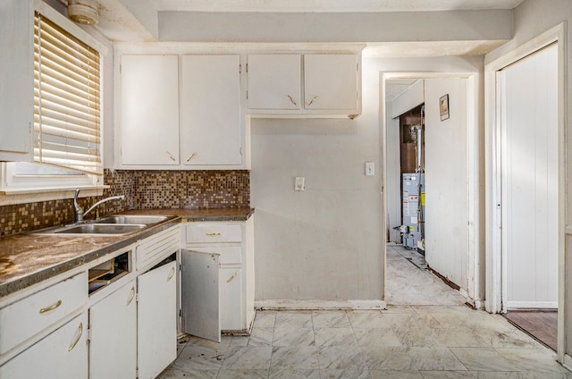 kitchen featuring tasteful backsplash, gas water heater, sink, and white cabinets