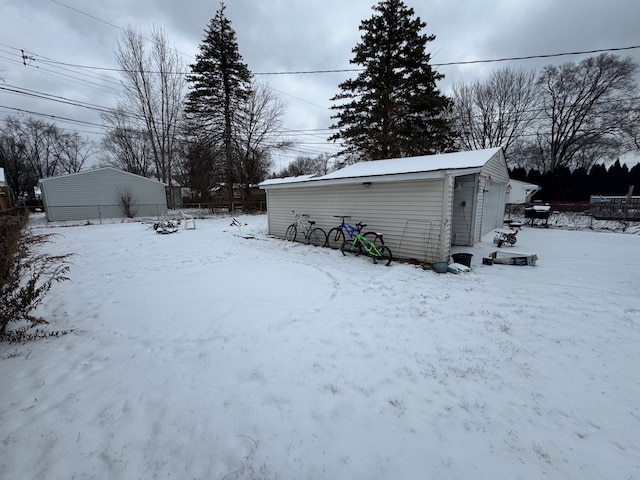 snowy yard with a garage and an outbuilding