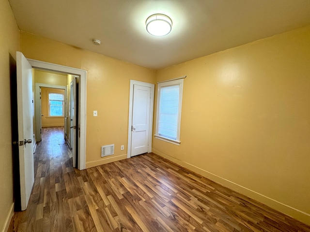 unfurnished bedroom with dark wood-type flooring and a closet