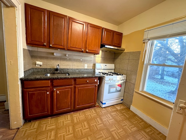 kitchen featuring sink, dark stone counters, white gas range oven, decorative backsplash, and light parquet floors