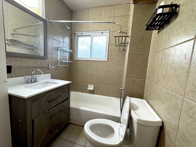 full bathroom featuring tiled shower / bath, tile walls, vanity, toilet, and tile patterned floors