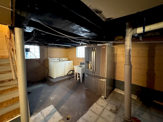 basement with stainless steel refrigerator with ice dispenser, sink, a wealth of natural light, and washer and clothes dryer