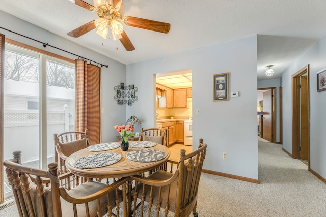 dining space featuring ceiling fan, light colored carpet, and a textured ceiling