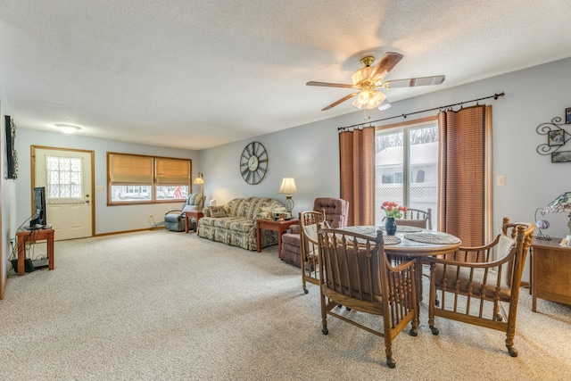 dining area with ceiling fan, a wealth of natural light, light colored carpet, and a textured ceiling