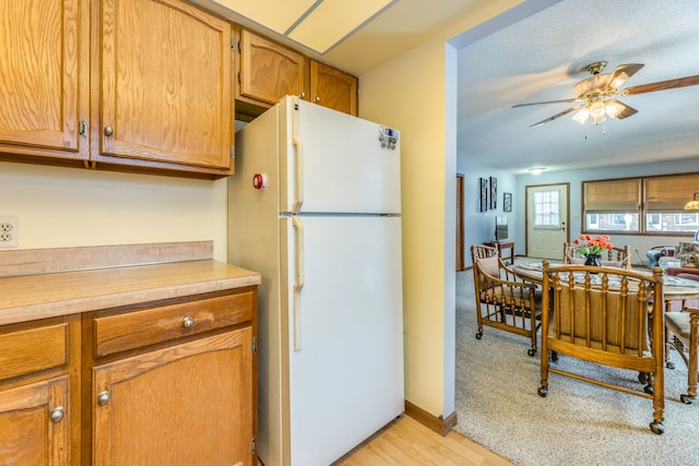 kitchen featuring white fridge, light wood-type flooring, and ceiling fan