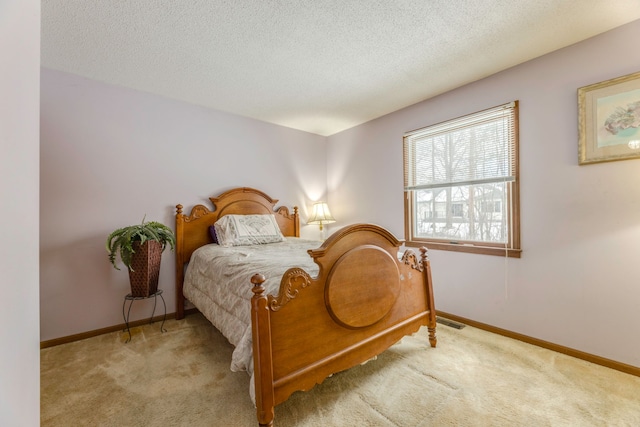 bedroom featuring light colored carpet and a textured ceiling