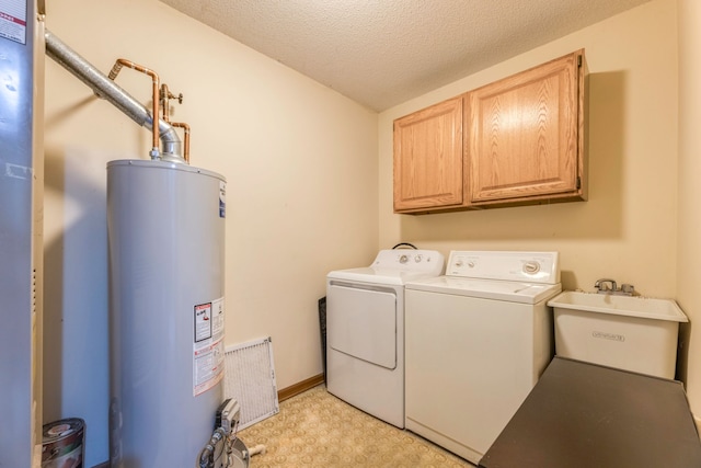 washroom with sink, gas water heater, cabinets, a textured ceiling, and washer and clothes dryer