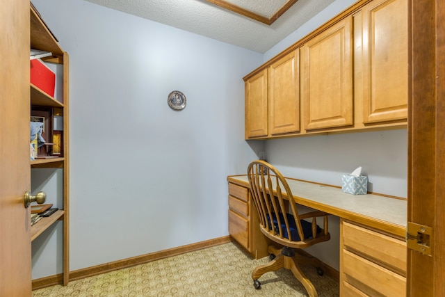 office area with built in desk and a textured ceiling