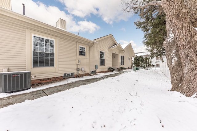 snow covered property with central air condition unit