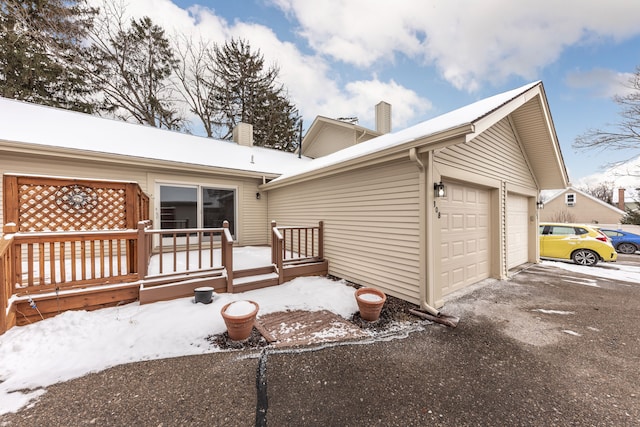 snow covered house featuring a wooden deck and a garage