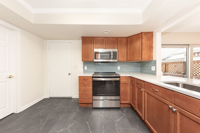 kitchen featuring backsplash, a tray ceiling, ornamental molding, and stainless steel appliances