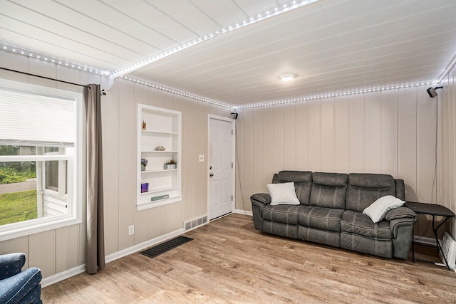 living room with built in shelves and hardwood / wood-style flooring