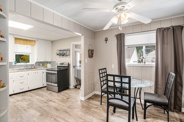 kitchen featuring white cabinetry, stainless steel range with electric stovetop, sink, and a wealth of natural light