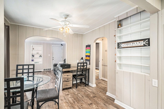 dining space featuring hardwood / wood-style flooring, ceiling fan, ornamental molding, and built in features