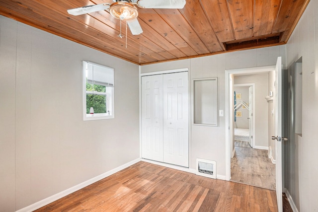 unfurnished bedroom featuring wood ceiling, ceiling fan, wood-type flooring, ornamental molding, and a closet