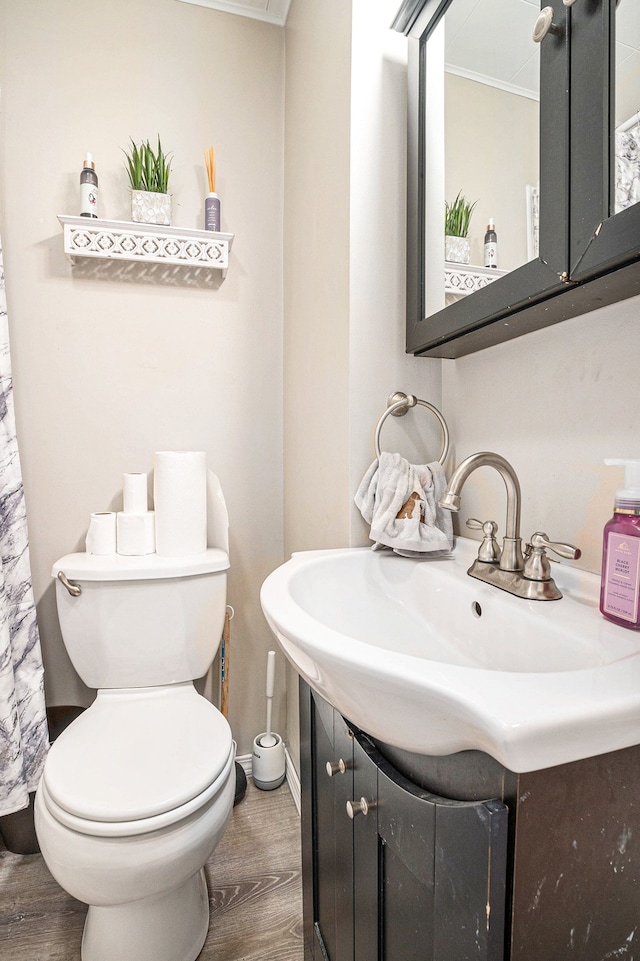 bathroom featuring ornamental molding, wood-type flooring, vanity, and toilet