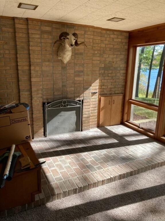 interior space featuring carpet floors, a large fireplace, and brick wall