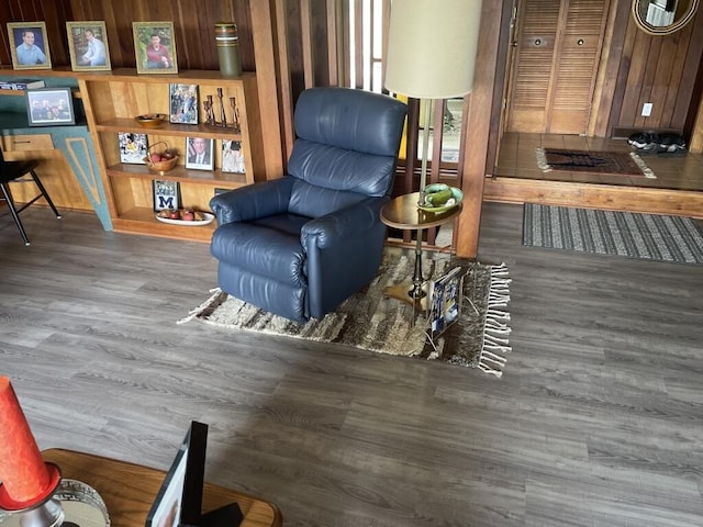 living area with wooden walls and dark hardwood / wood-style flooring