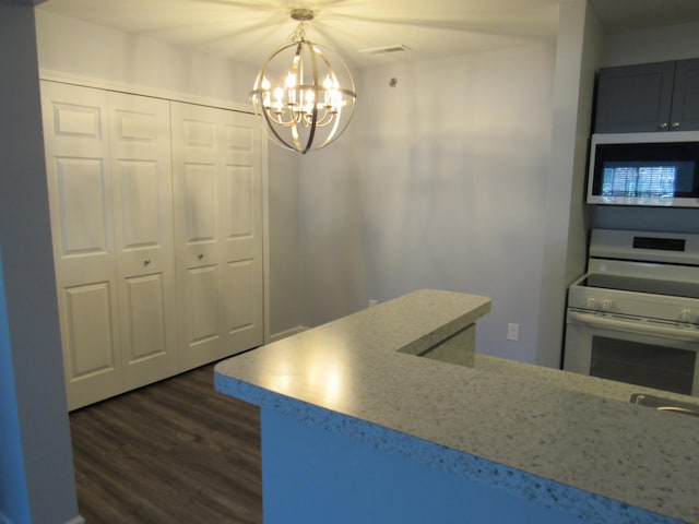 kitchen featuring dark wood-type flooring, white electric range, light stone counters, a chandelier, and pendant lighting