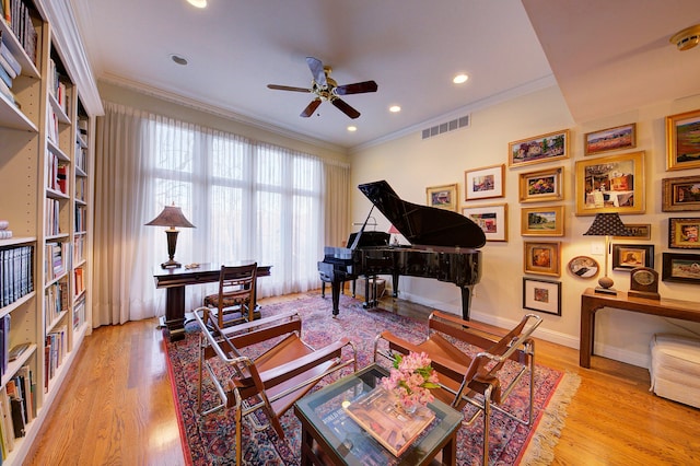 living area with crown molding, ceiling fan, and light wood-type flooring