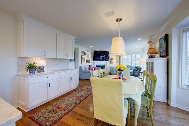 dining area with ornamental molding and dark hardwood / wood-style flooring