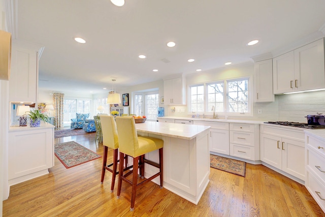 kitchen featuring a kitchen island, pendant lighting, white cabinetry, a kitchen bar, and gas stovetop