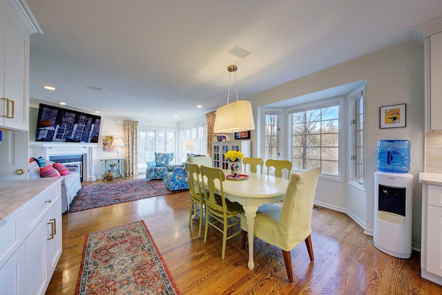 dining area with light hardwood / wood-style flooring and ornamental molding