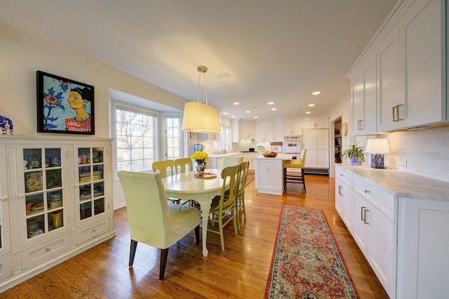 dining space featuring sink, wood-type flooring, and ornamental molding