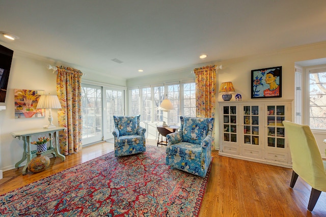 living area featuring ornamental molding and light hardwood / wood-style flooring