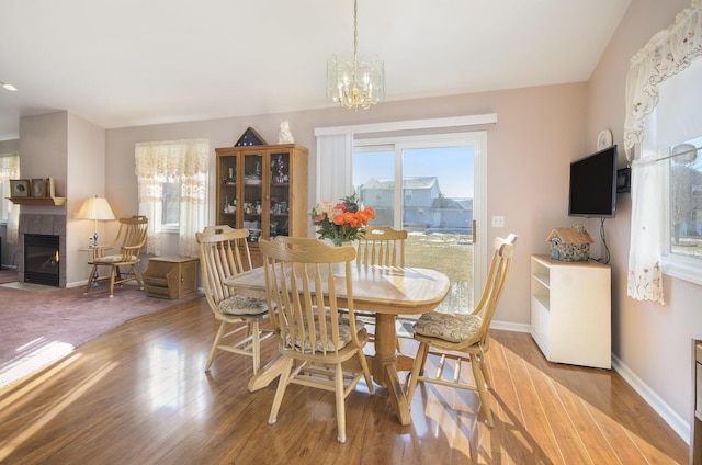 dining room featuring wood-type flooring, an inviting chandelier, and a fireplace