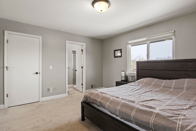 bedroom with ensuite bath and light colored carpet