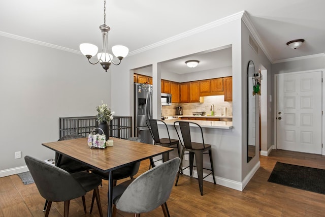 dining space with a notable chandelier, crown molding, wood-type flooring, and sink