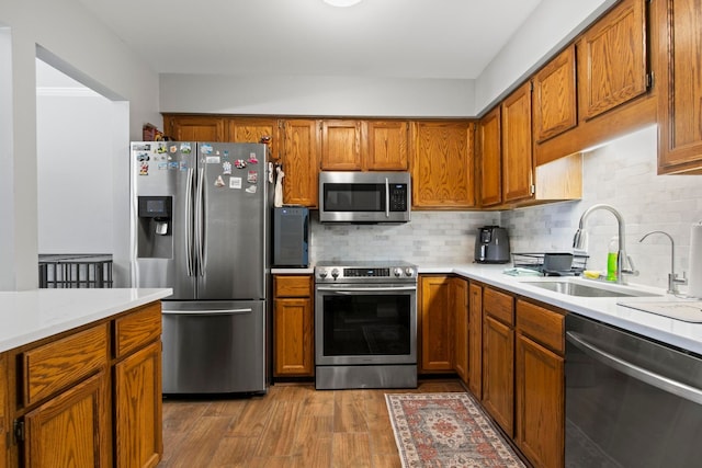 kitchen featuring wood-type flooring, appliances with stainless steel finishes, sink, and backsplash