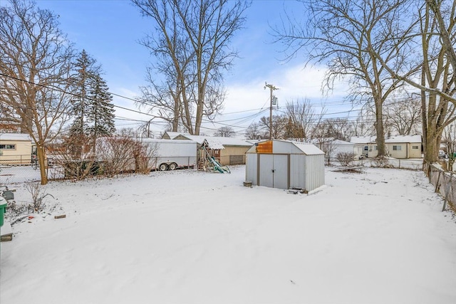 yard covered in snow with a playground and a storage shed