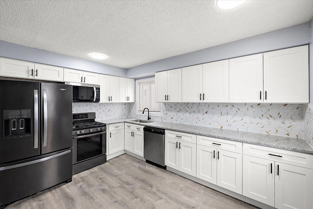 kitchen featuring sink, backsplash, stainless steel appliances, light stone countertops, and white cabinets