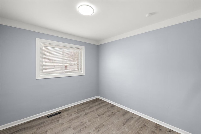 spare room with ornamental molding and light hardwood / wood-style floors