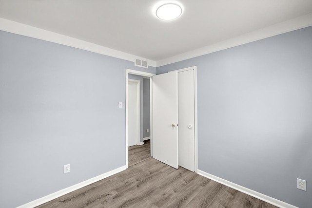 spare room with ornamental molding and light hardwood / wood-style floors