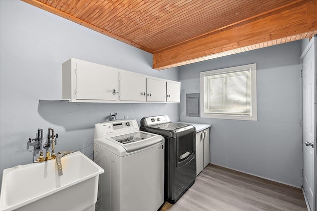 clothes washing area with sink, cabinets, washing machine and clothes dryer, light hardwood / wood-style floors, and wooden ceiling